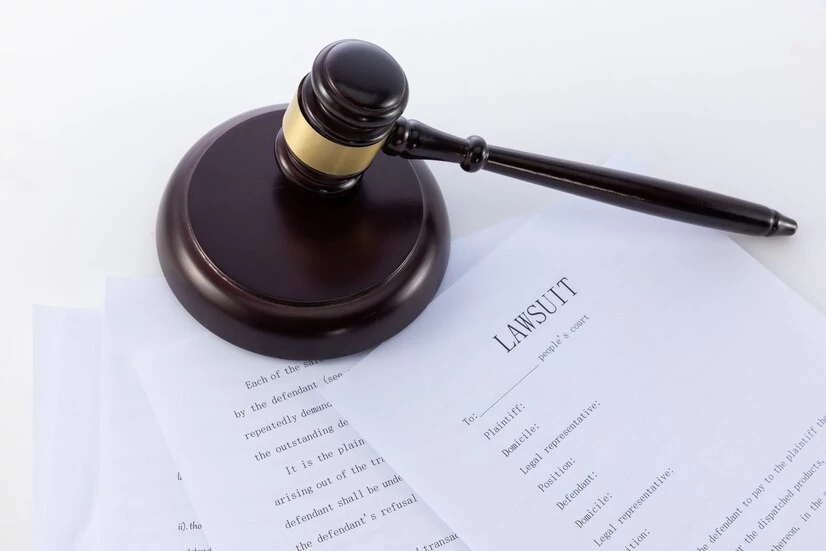 A gavel on top of papers that read "lawsuit"